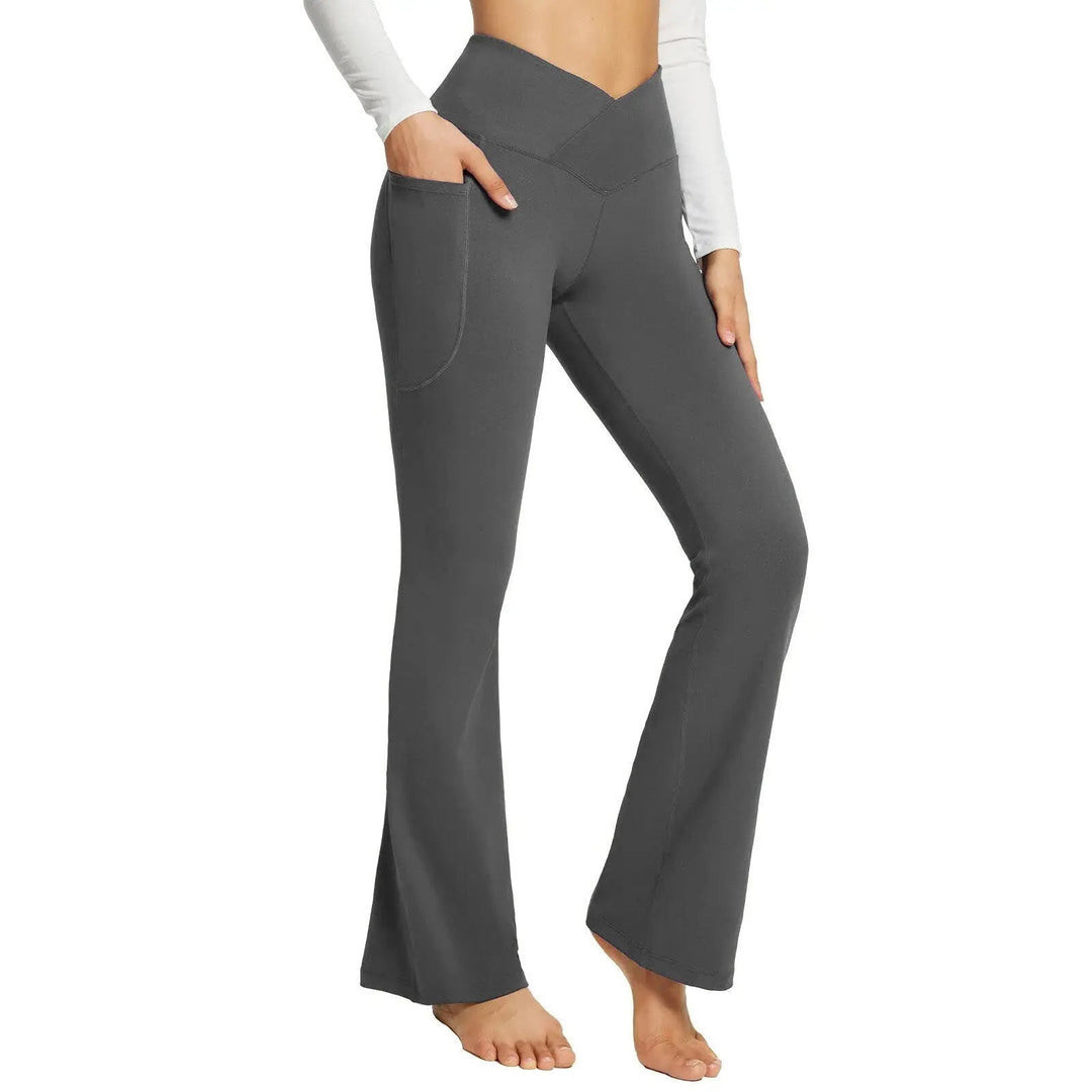 Pantaloni yoga a vita alta grigi con tasche, design a campana, indossati da donna. Abbigliamento sportivo comodo ed elegante per fitness e tempo libero.