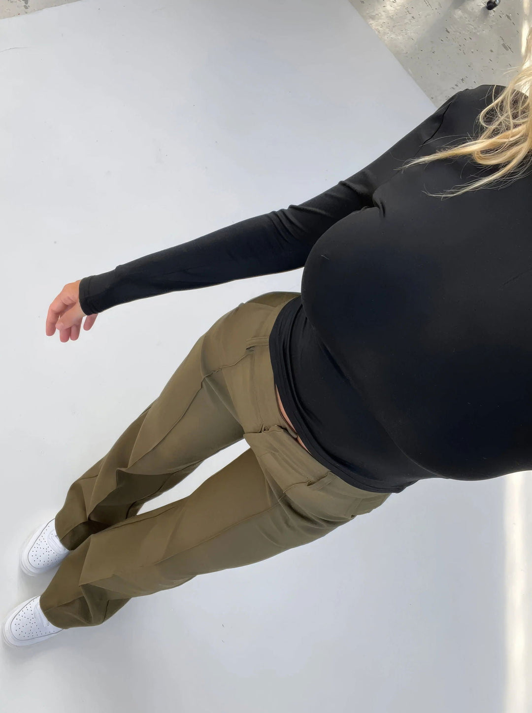 Donna in maglia nera a maniche lunghe e pantaloni cargo verde oliva, scarpe bianche. Moda casual femminile, abbigliamento autunnale.