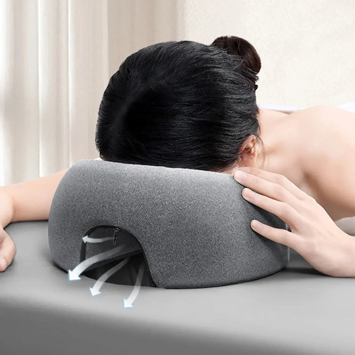 Cuscino ergonomico grigio per massaggi, supporto viso con fori di ventilazione, ideale per spa e relax, comfort e traspirabilità ottimali.