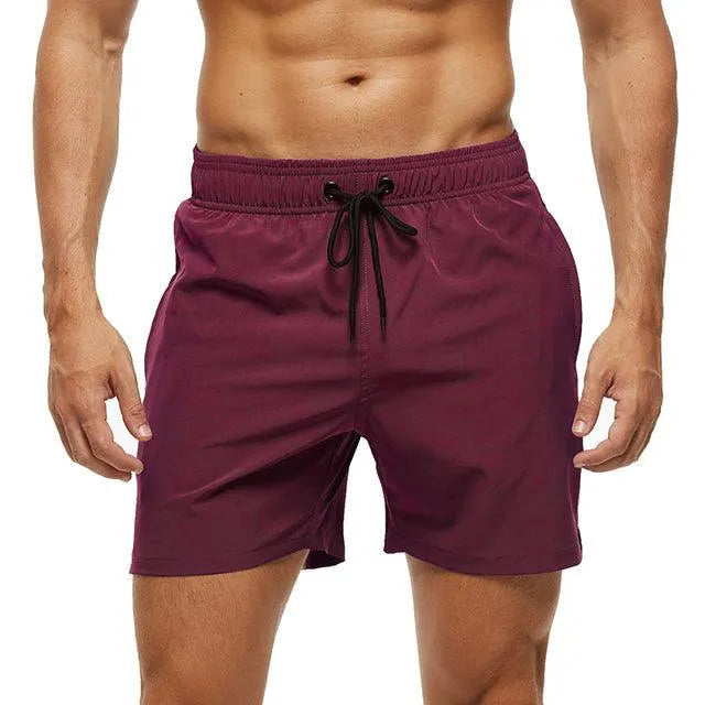 Uomo in pantaloncini da bagno bordeaux, elastico in vita con laccio nero. Costume mare estivo, moda uomo, abbigliamento sportivo.