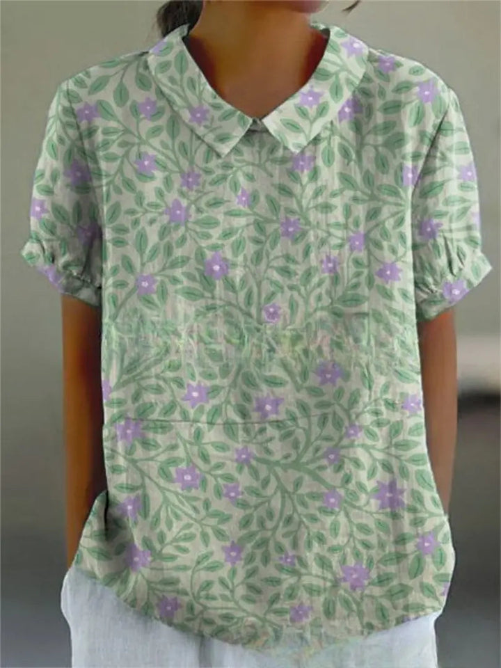 Camicia donna estiva a maniche corte con stampa floreale verde e viola, colletto classico, tessuto leggero, ideale per look casual e freschi.