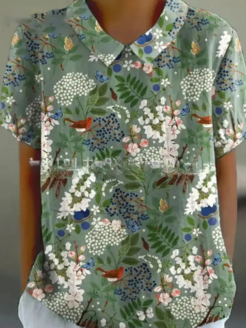 Camicia donna a maniche corte con stampa floreale verde, colletto classico, farfalle e fiori colorati. Moda estiva casual elegante.