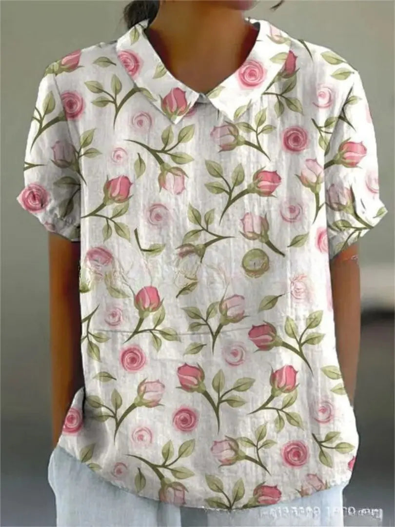 Camicia donna a maniche corte con stampa floreale rosa su sfondo bianco, colletto classico. Elegante e casual, perfetta per la primavera.
