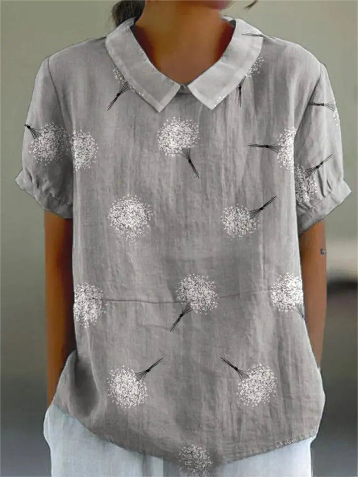 Camicia grigia da donna in lino con stampa di soffioni bianchi, maniche corte e colletto classico. Elegante e casual, perfetta per l'estate.