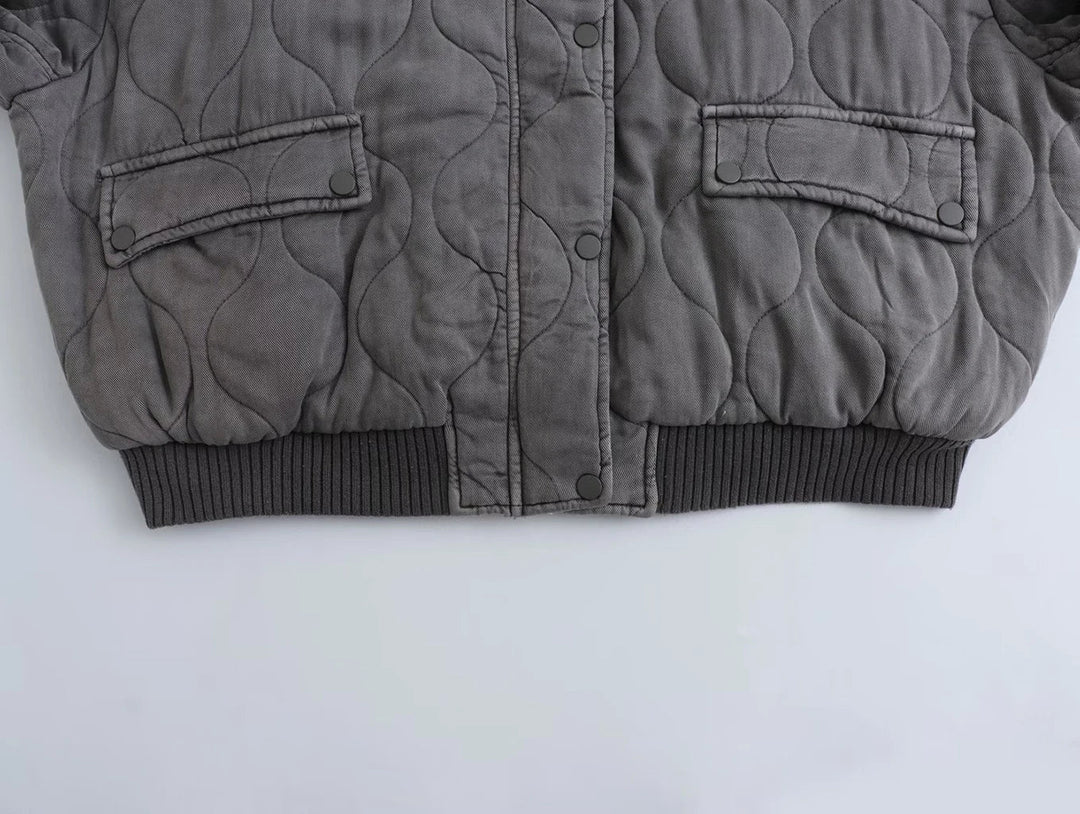 Giacca trapuntata grigia invernale, design moderno, chiusura a bottoni, tasche frontali, ideale per moda uomo, abbigliamento caldo e casual.