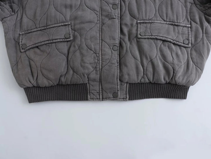 Giacca trapuntata grigia invernale, design moderno, chiusura a bottoni, tasche frontali, ideale per moda uomo, abbigliamento caldo e casual.