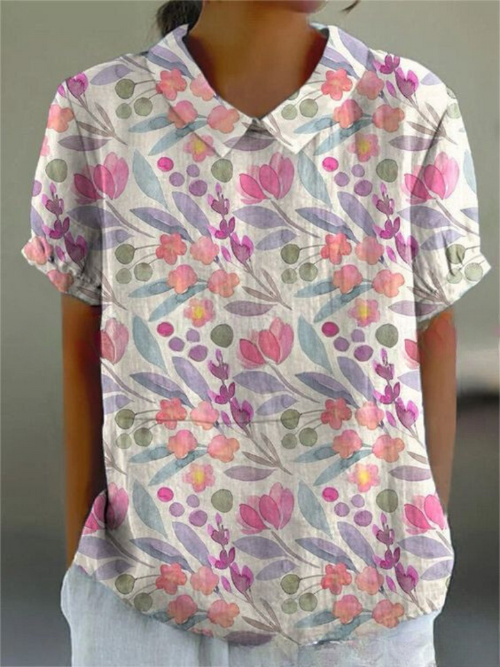 Camicia donna a maniche corte con stampa floreale colorata, colletto classico, sfondo bianco. Stile casual estivo, moda femminile.