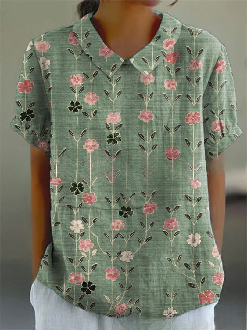 Camicia donna verde con motivo floreale rosa e bianco, maniche corte, colletto classico. Stile casual estivo, tessuto leggero e traspirante.