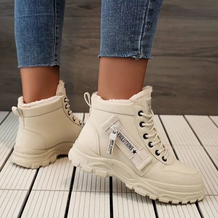 Stivaletti beige da donna con pelliccia, suola robusta e lacci neri, indossati con jeans. Scarpe invernali moda, comode e calde.