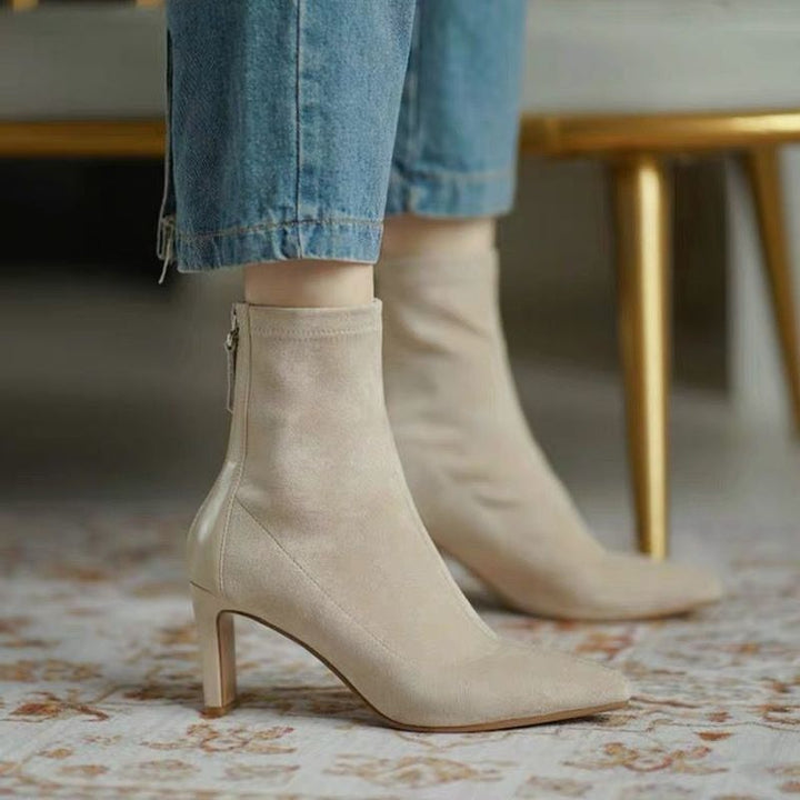 Stivaletti beige in pelle scamosciata con tacco a spillo, chiusura a zip, indossati con jeans. Eleganti e alla moda, ideali per l'autunno.