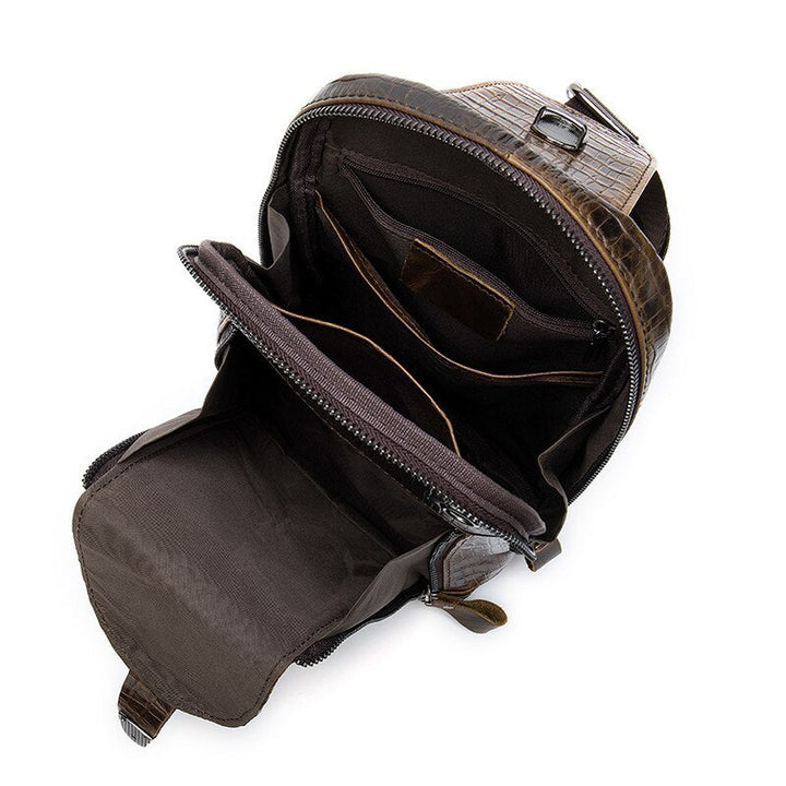 Zaino in pelle marrone con texture coccodrillo, aperto per mostrare scomparti interni spaziosi e tasche multiple. Design elegante e funzionale.