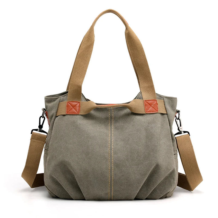 Borsa a tracolla in tela verde oliva con manici marroni, dettagli in pelle, e tracolla regolabile. Design casual e spazioso per uso quotidiano.