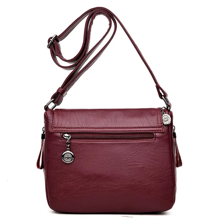 Borsa a tracolla in pelle sintetica bordeaux con cerniera frontale e charm decorativo. Elegante e pratica per uso quotidiano.