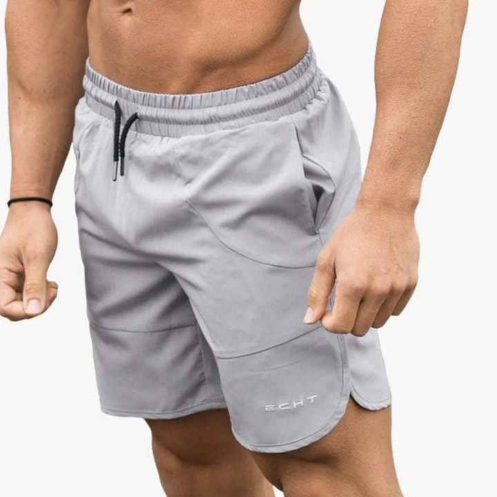 Shorts sportivi grigi da uomo, tessuto leggero, elastico in vita con laccio, ideali per palestra e fitness. Design moderno e confortevole.