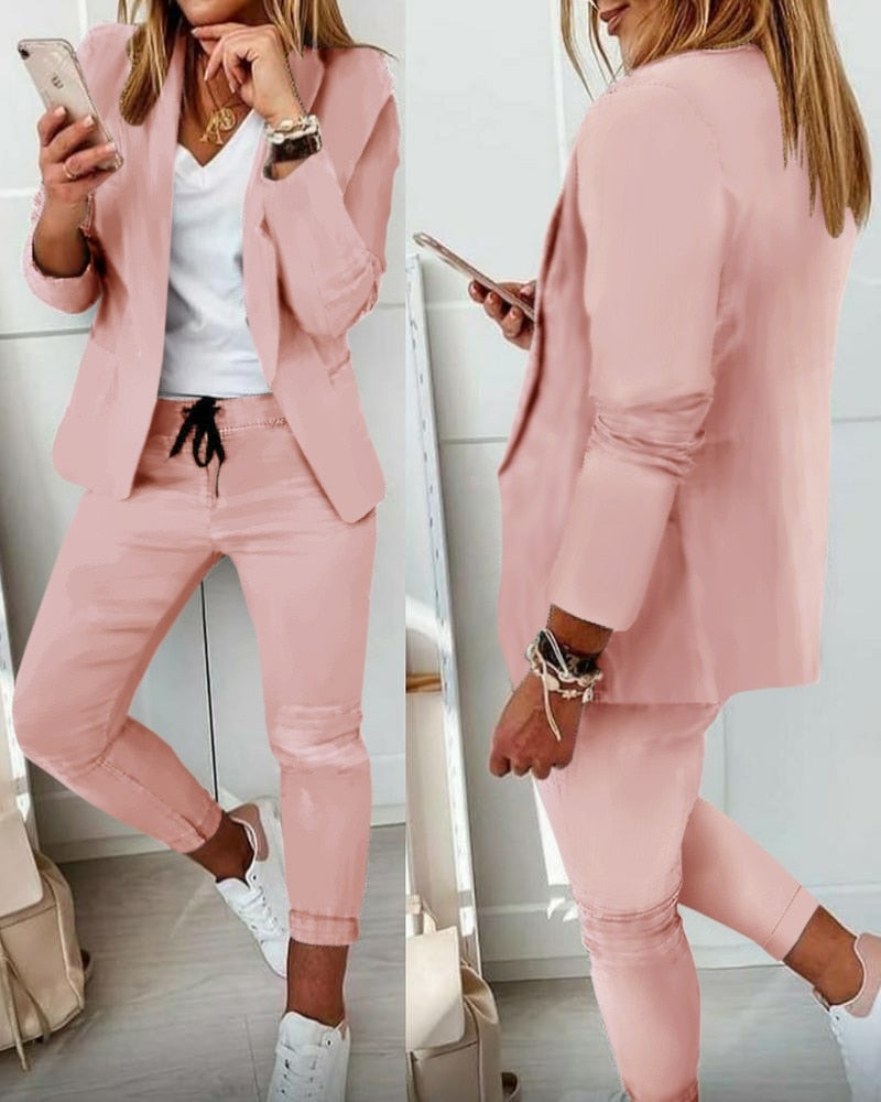 Donna in completo rosa elegante, giacca e pantaloni, con smartphone. Look casual-chic, moda femminile, abbigliamento primaverile, tendenze 2023.