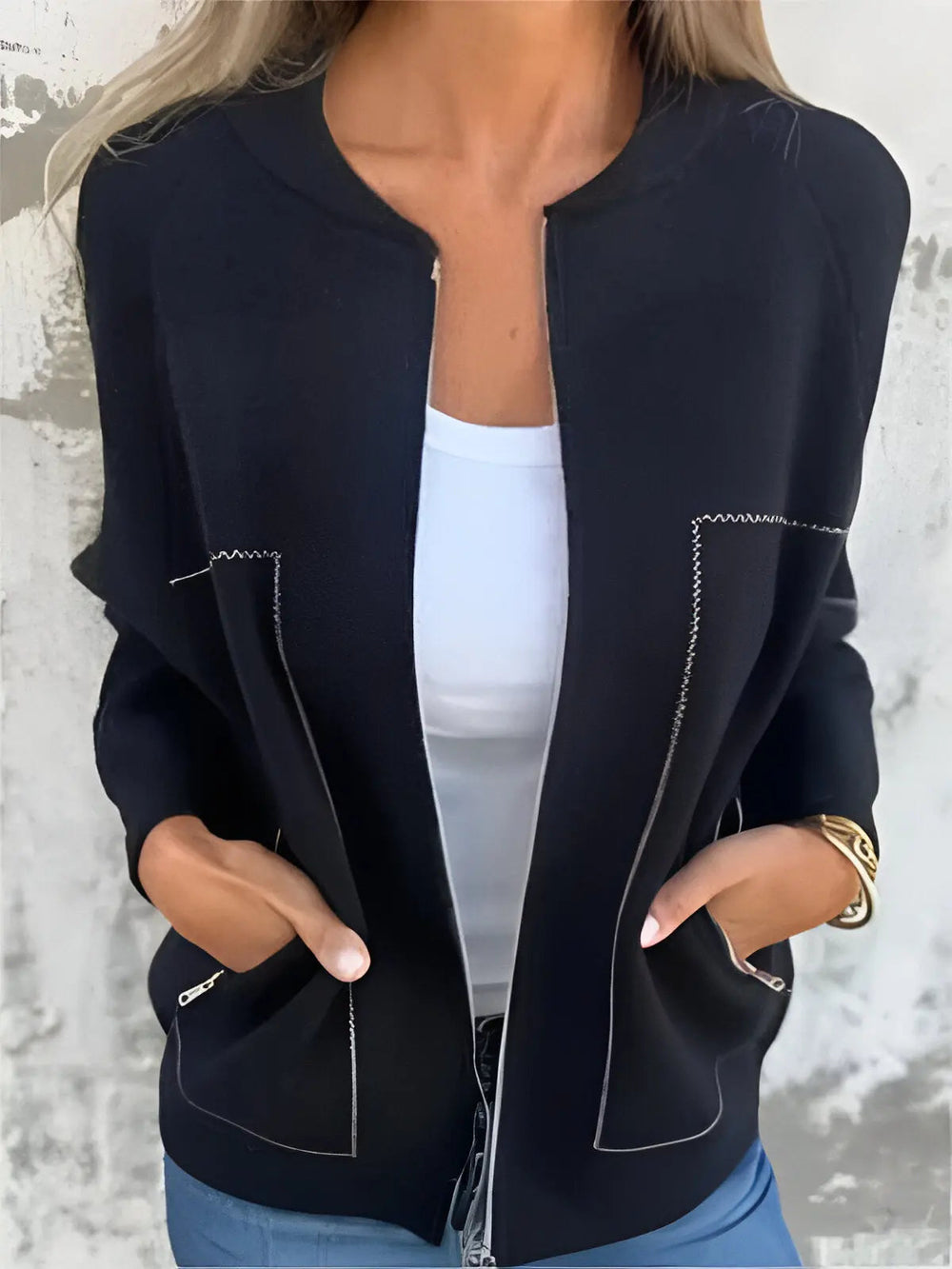 Giacca nera da donna con cuciture bianche, indossata sopra una maglietta bianca. Design elegante, casual, perfetto per moda autunnale.