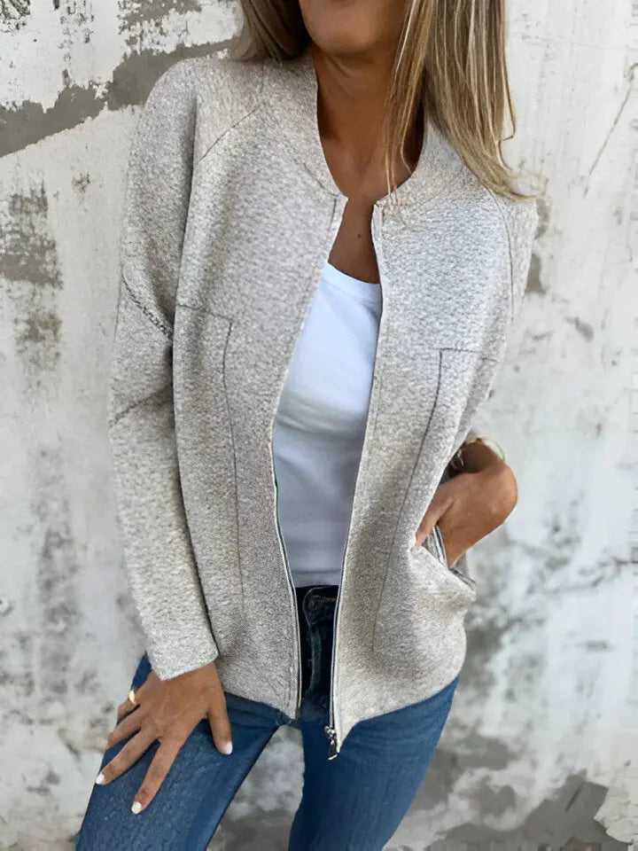 Giacca donna beige in tessuto morbido, con zip frontale, indossata su maglietta bianca e jeans. Look casual chic, moda autunno.