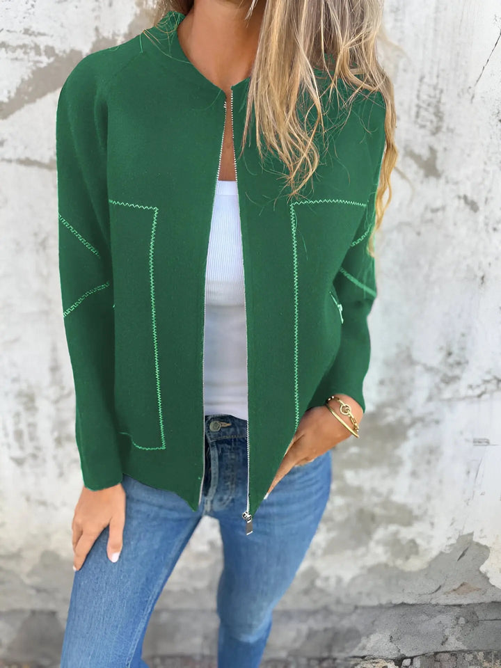 Giacca verde donna, stile casual, con cuciture a contrasto, indossata su top bianco e jeans. Moda autunnale, abbigliamento femminile trendy.