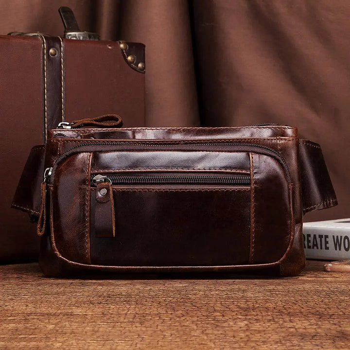 Marsupio in pelle marrone vintage su tavolo di legno, con cerniere e tasche multiple. Accessorio moda uomo, stile retrò, ideale per viaggi.