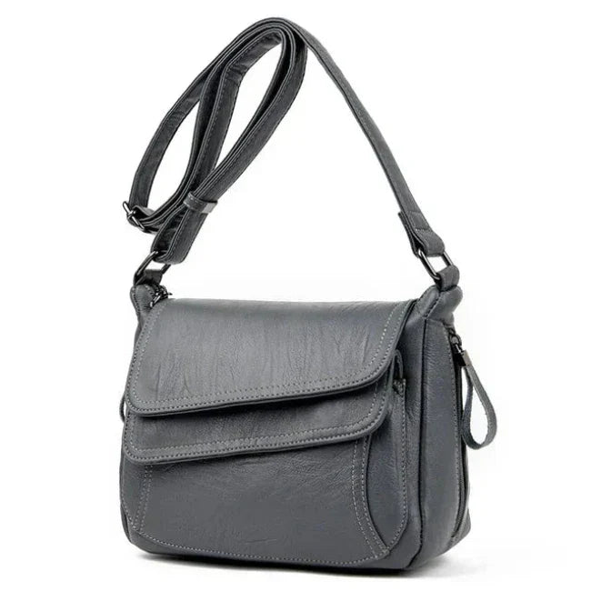 Borsa a tracolla in pelle grigia, design elegante e moderno, con tasche multiple e chiusura a zip. Accessorio moda donna, versatile e pratico.