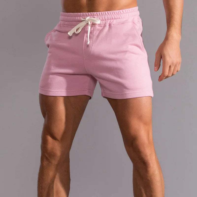 Shorts da uomo rosa in cotone, con elastico in vita e laccio bianco, ideali per sport e tempo libero. Design moderno e confortevole.