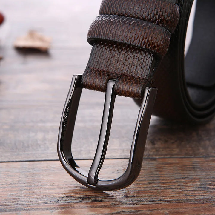 Cintura in pelle marrone con fibbia metallica lucida su sfondo in legno. Accessorio moda uomo elegante, alta qualità, stile classico.