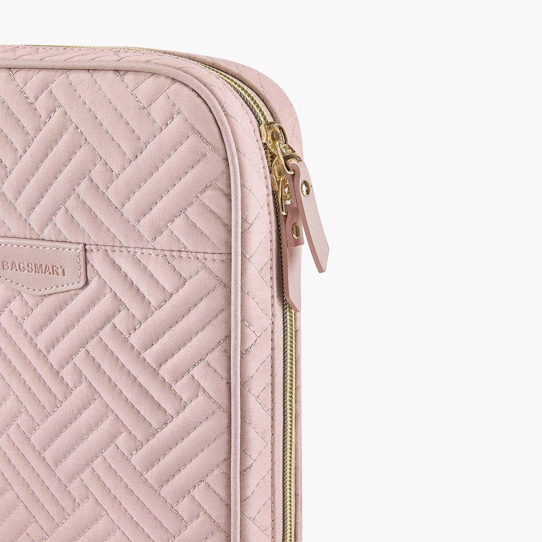 Custodia laptop rosa trapuntata con motivo a spina di pesce, cerniera dorata e marchio visibile. Accessorio elegante e protettivo per computer portatile.