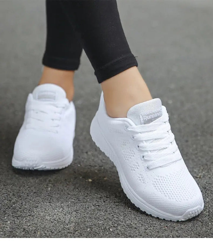 Scarpe da corsa bianche da donna su strada asfaltata, design traspirante, suola antiscivolo, ideali per jogging e attività sportive all'aperto.