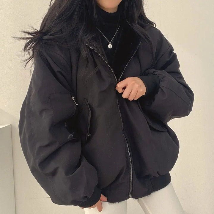 Giacca oversize nera da donna, stile casual, con zip frontale e tasche, indossata su maglione nero. Moda autunnale, abbigliamento femminile trendy.