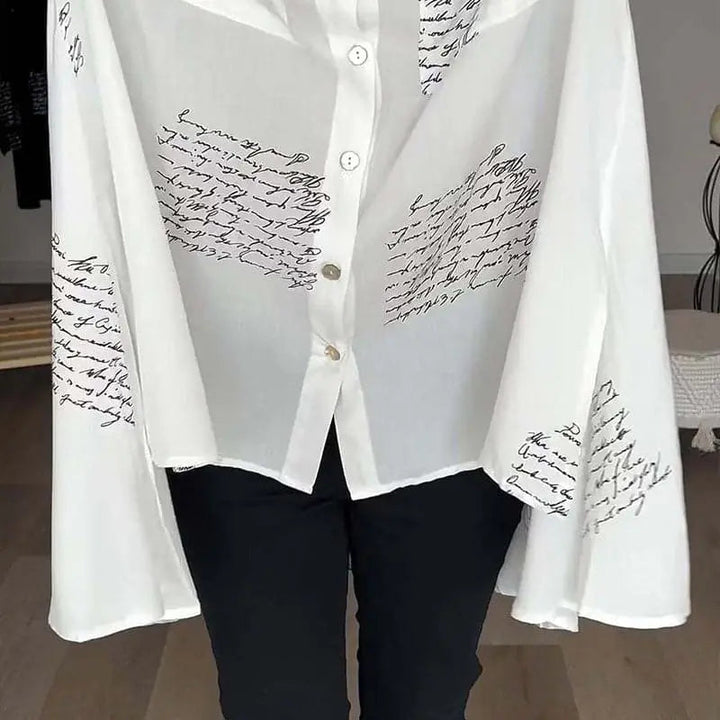 Camicia bianca trasparente con scritte nere, maniche ampie, abbottonatura frontale, stile elegante e moderno, perfetta per moda femminile casual.
