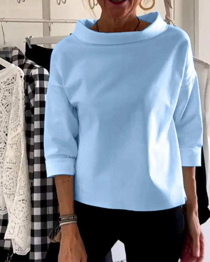 Maglia donna azzurra a maniche lunghe, collo alto, abbinata a pantaloni neri. Moda casual elegante, abbigliamento femminile autunnale.