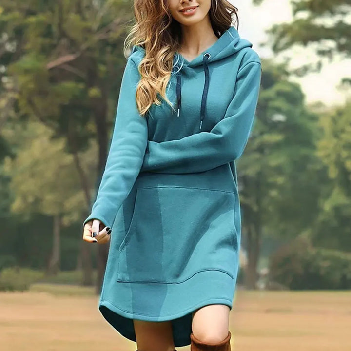 Donna con abito felpa con cappuccio blu, maniche lunghe, tasca frontale, in un parco. Moda casual autunnale, abbigliamento comodo per esterni.