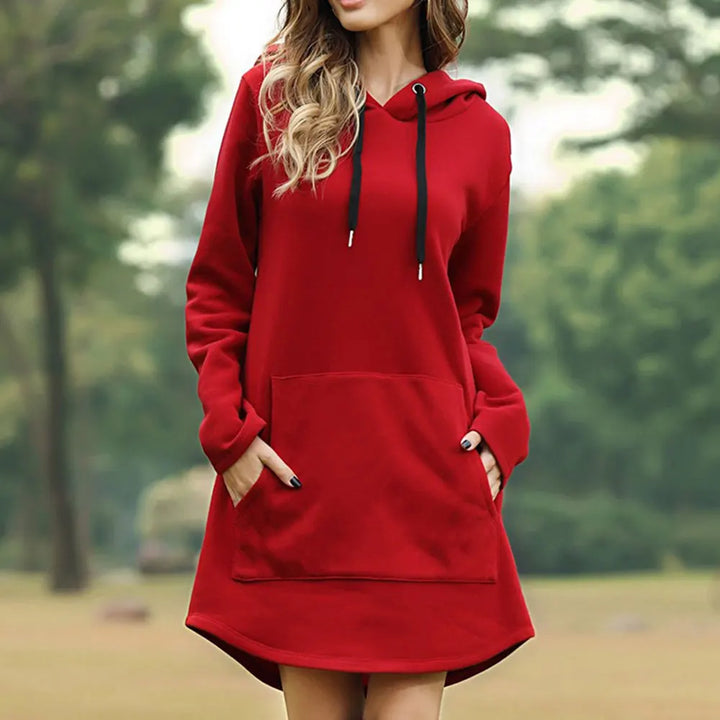 Donna con felpa rossa con cappuccio, tasca frontale e lacci neri, in un parco. Abbigliamento casual autunnale, moda donna, stile confortevole.