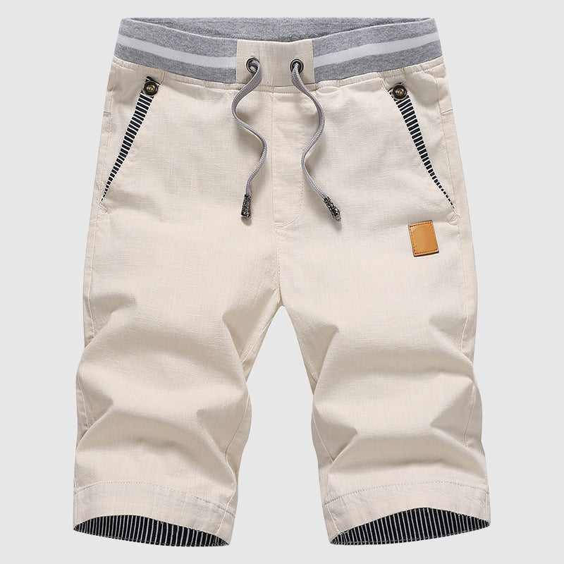 Pantaloncini beige da uomo con coulisse, tasche con zip, dettagli a righe grigie. Ideali per moda estiva casual. Tessuto leggero e confortevole.