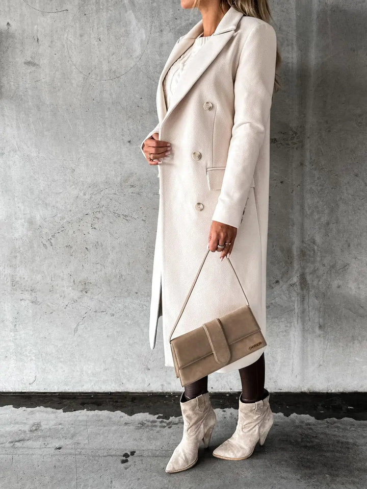 Cappotto lungo beige elegante, donna in posa con borsa a tracolla e stivali coordinati, moda autunno inverno, abbigliamento femminile chic.