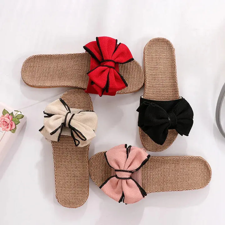 Quattro paia di ciabatte estive in paglia con fiocco colorato: rosso, nero, beige e rosa. Design elegante, perfette per la moda estiva.