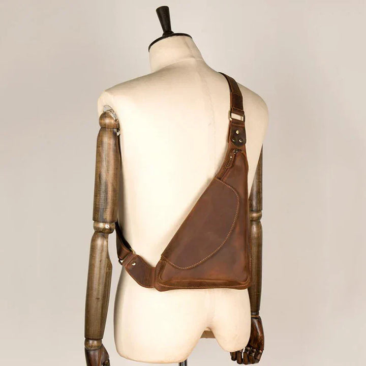 Zaino monospalla in pelle marrone su manichino, design ergonomico, stile vintage, ideale per uomo, accessorio moda, alta qualità artigianale.