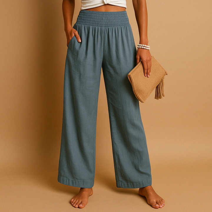Pantaloni larghi donna blu, vita alta elasticizzata, tasche laterali, abbinati a top bianco e pochette beige. Moda casual estiva.