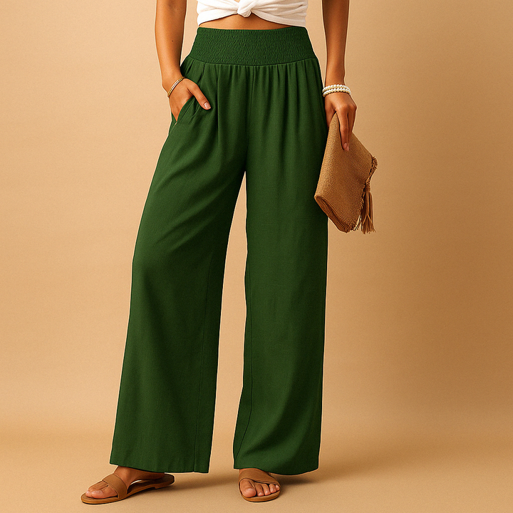 Pantaloni verdi donna a vita alta, larghi, in tessuto leggero. Moda estiva casual, abbinati a sandali e borsa in paglia.