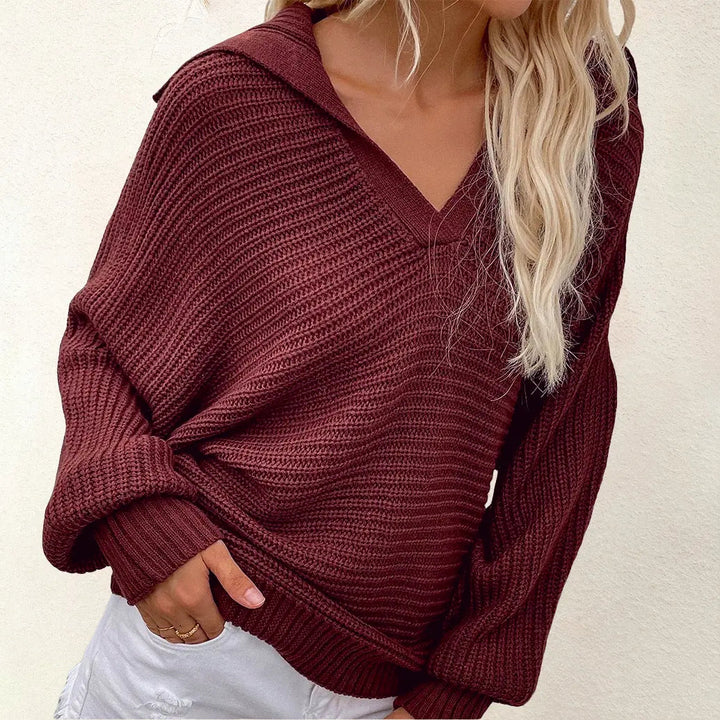 Maglione donna in maglia a coste bordeaux, maniche lunghe, scollo a V, abbinato a pantaloni bianchi. Look casual autunnale.