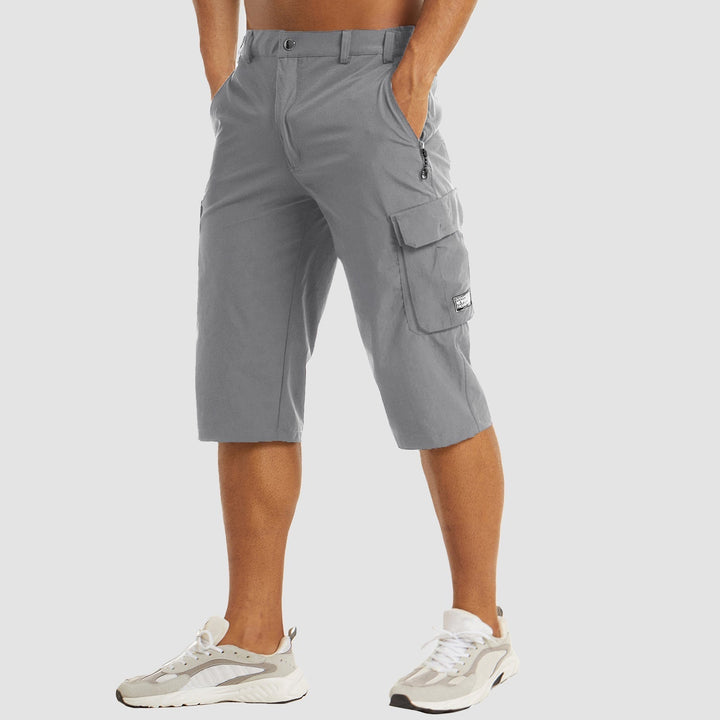 Bermuda cargo uomo grigio, tasche multiple, lunghezza al ginocchio, tessuto leggero, stile casual, perfetto per estate, abbinato a sneakers bianche.