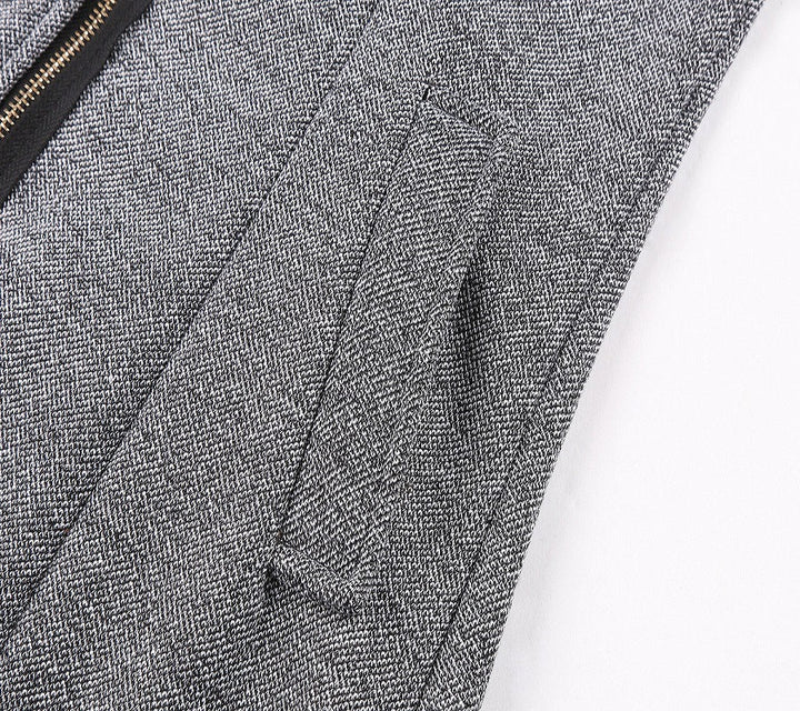 Giacca in tessuto grigio a spina di pesce con cerniera nera e tasca laterale. Elegante e moderna, ideale per abbigliamento formale e casual.