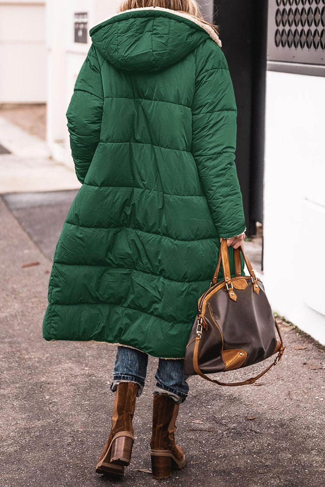 Donna con cappotto verde lungo, borsa in pelle marrone, stivali marroni su strada urbana. Moda invernale, abbigliamento casual elegante.