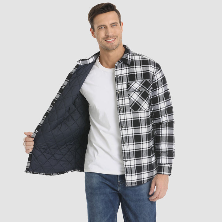 Uomo con camicia a quadri bianca e nera, interno trapuntato, indossa jeans blu e maglietta bianca. Moda casual maschile, abbigliamento autunnale.
