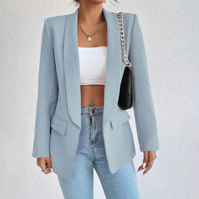 Giacca blazer donna azzurra, elegante e moderna, abbinata a top bianco e jeans. Accessorio: borsa nera a tracolla con catena dorata.