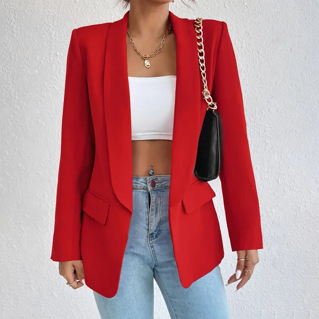 Giacca rossa elegante da donna, abbinata a top bianco e jeans. Accessori: collana dorata e borsa nera a catena. Moda casual chic.