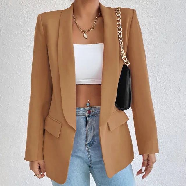 Giacca blazer donna marrone elegante, abbinata a top bianco e jeans. Accessori: collana oro e borsa nera a tracolla. Moda casual chic.