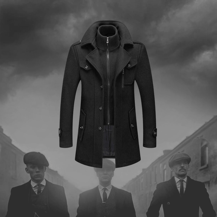 Cappotto uomo elegante nero, stile vintage, con colletto alto e bottoni, ispirato alla moda retrò. Sfondo grigio con figure sfocate.