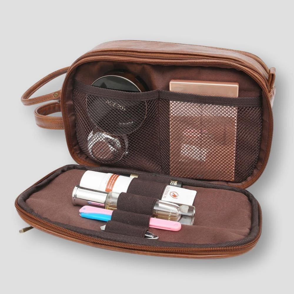 Astuccio da viaggio in pelle marrone aperto con scomparti, contenente cosmetici e accessori. Ideale per organizzare trucchi e prodotti di bellezza.