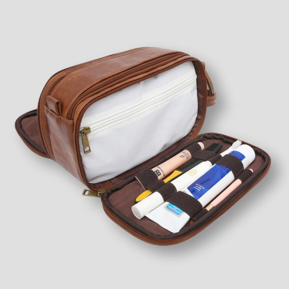 Astuccio da viaggio in pelle marrone con cerniera, scomparti interni bianchi, contenente articoli da toeletta. Accessorio elegante e funzionale.